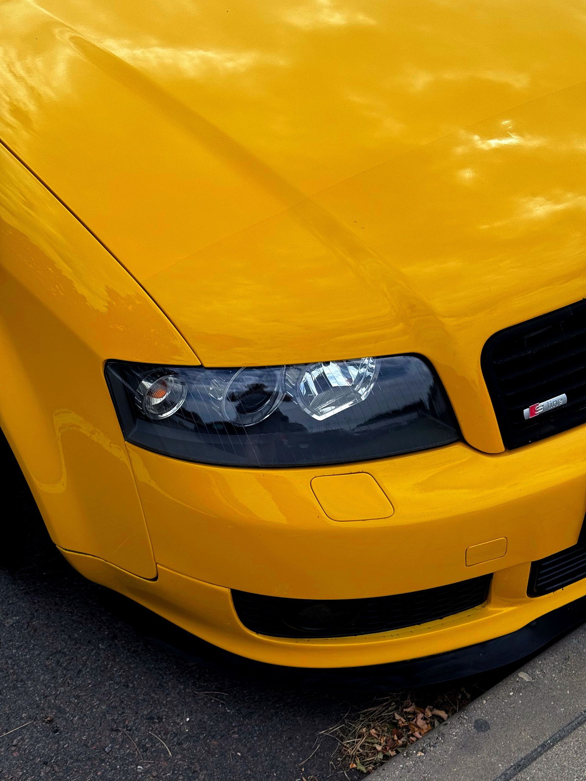 Detailed image of a bright yellow Audi car showcasing the front headlights and sleek design.