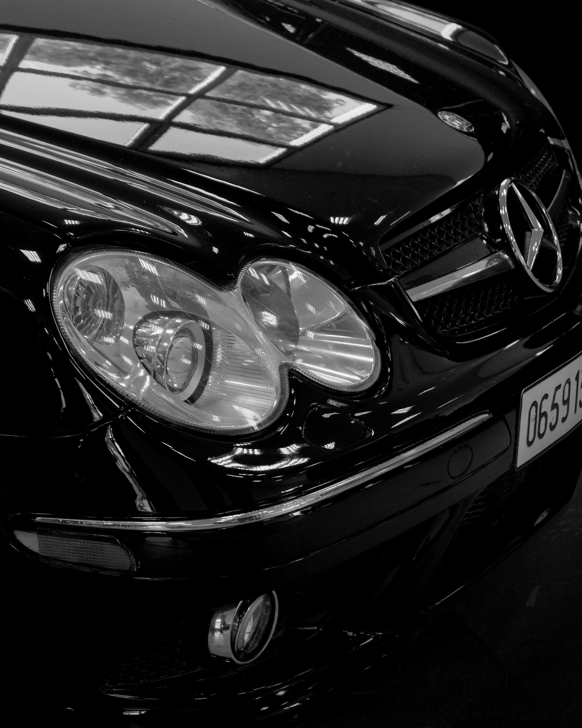 Elegant black Mercedes Benz with shining headlights, close-up shot highlighting luxury and design.